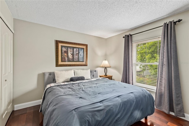 bedroom featuring dark wood-type flooring, a closet, and a textured ceiling