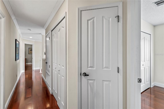 hall featuring a textured ceiling, dark wood-type flooring, and crown molding