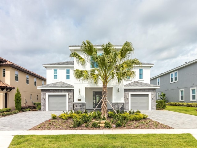 view of front facade featuring a garage, stone siding, decorative driveway, and stucco siding