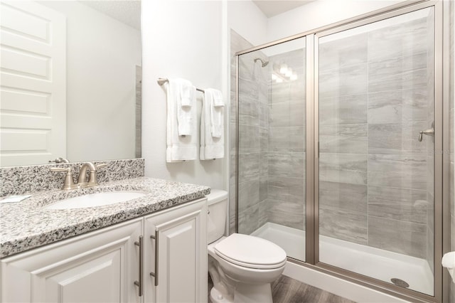 full bath featuring toilet, a stall shower, wood finished floors, and vanity