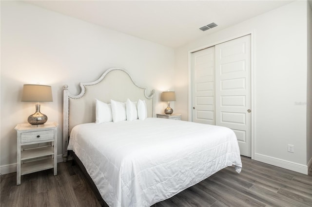 bedroom featuring baseboards, visible vents, dark wood-type flooring, and a closet