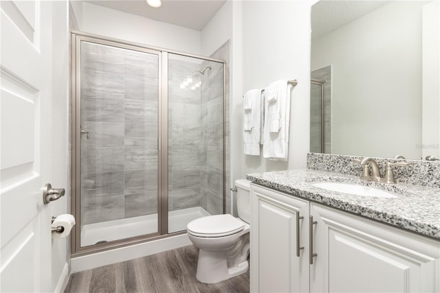 bathroom featuring a stall shower, vanity, toilet, and wood finished floors