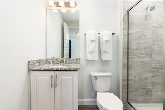 bathroom featuring a stall shower, vanity, toilet, and baseboards