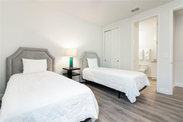 bedroom with hardwood / wood-style floors, ensuite bathroom, and a closet