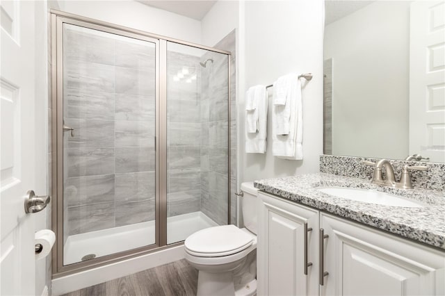 full bath with toilet, a shower stall, wood finished floors, and vanity