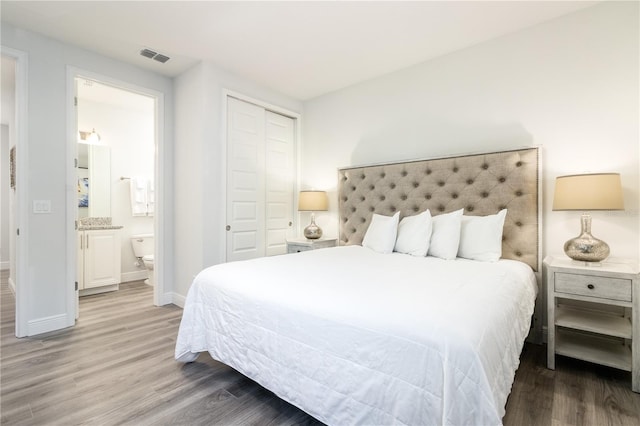 bedroom featuring a closet, visible vents, connected bathroom, wood finished floors, and baseboards