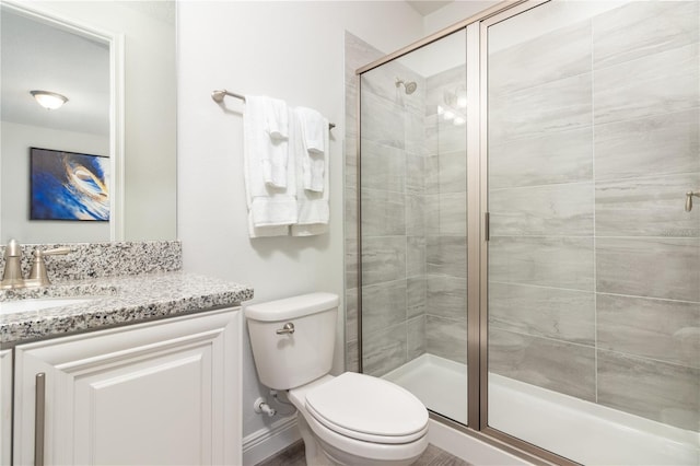 bathroom featuring a shower with shower door, vanity, and toilet