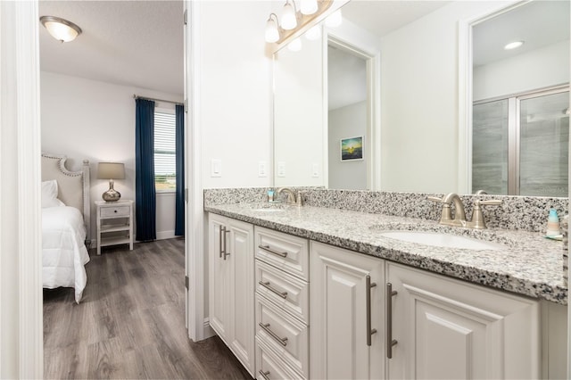 ensuite bathroom featuring double vanity, wood finished floors, ensuite bath, and a sink