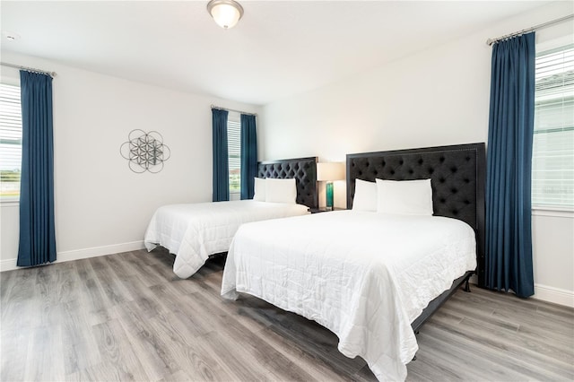 bedroom featuring multiple windows, wood finished floors, and baseboards