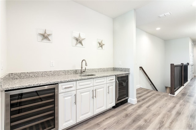 bar featuring light wood-type flooring, beverage cooler, a sink, and wet bar