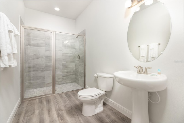 full bathroom with toilet, a stall shower, baseboards, and wood finished floors