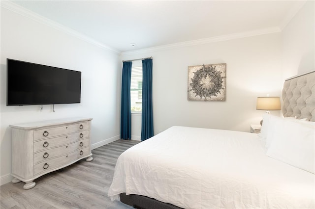 bedroom with light wood-style flooring, ornamental molding, and baseboards