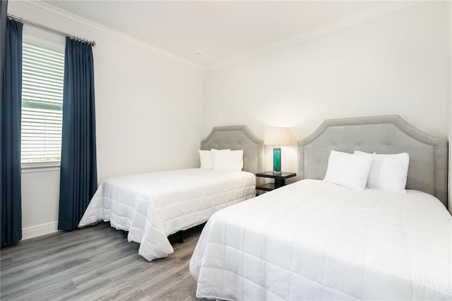 bedroom featuring baseboards, crown molding, and wood finished floors