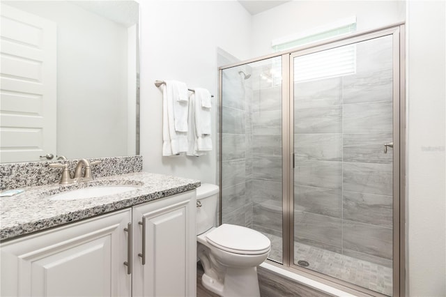 full bath with toilet, a shower stall, wood finished floors, and vanity