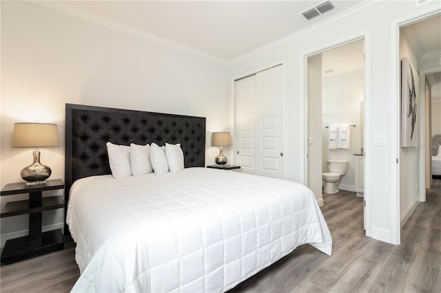 bedroom featuring a closet, visible vents, ornamental molding, wood finished floors, and baseboards