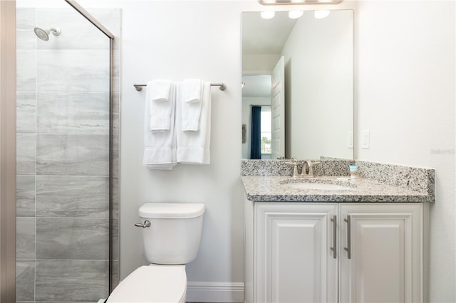 full bath with toilet, baseboards, a tile shower, and vanity