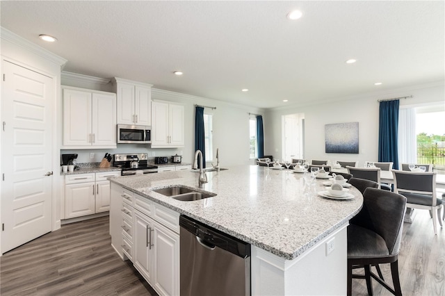 kitchen with stainless steel appliances, hardwood / wood-style floors, a center island with sink, and sink