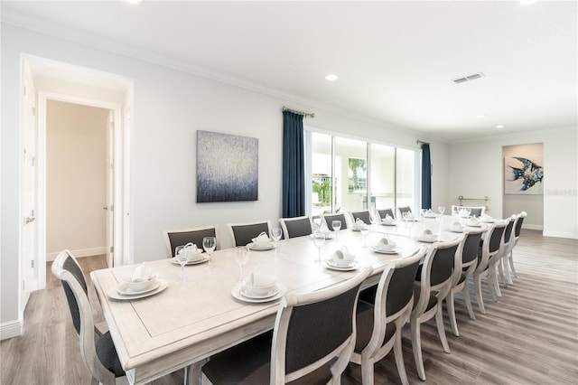 dining area featuring baseboards, light wood-type flooring, visible vents, and crown molding