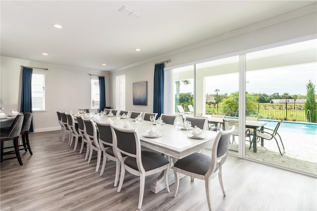 dining room with light hardwood / wood-style flooring and crown molding