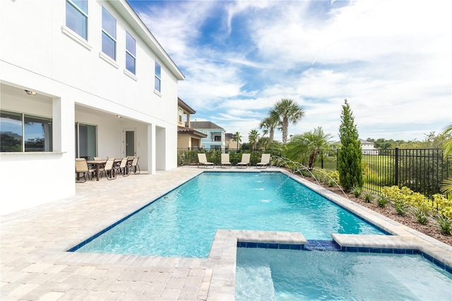 view of swimming pool with a pool with connected hot tub, fence, and a patio