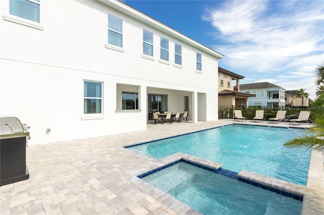 back of property with a pool with connected hot tub, fence, a patio, and stucco siding