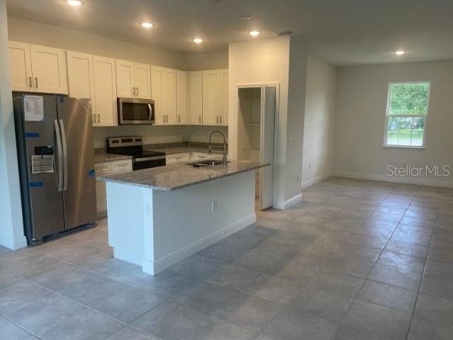 kitchen with white cabinetry, sink, light tile floors, and stainless steel appliances