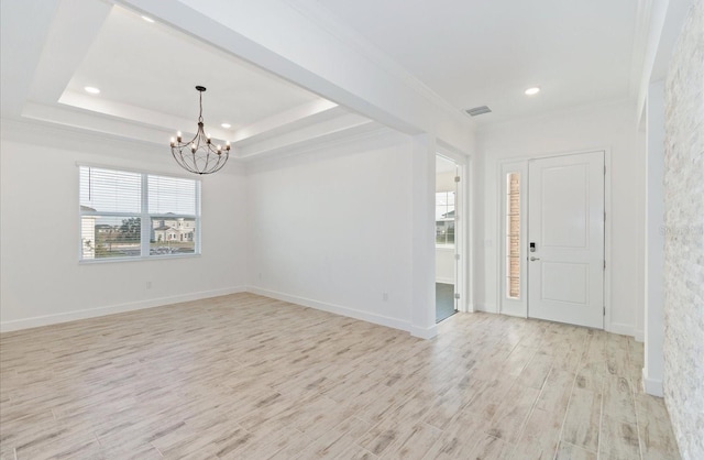 entrance foyer with a raised ceiling, crown molding, light hardwood / wood-style floors, and a notable chandelier