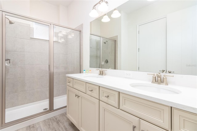 bathroom featuring a shower with door, dual bowl vanity, and hardwood / wood-style flooring