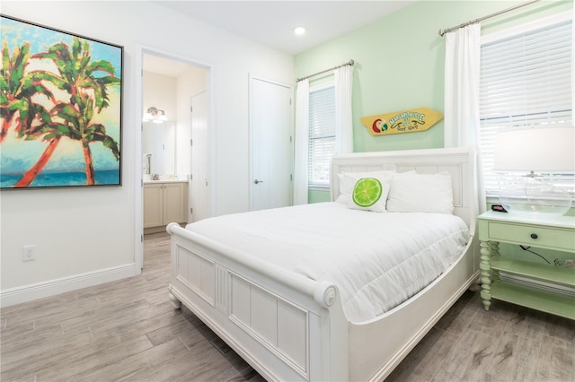 bedroom with light hardwood / wood-style flooring and ensuite bath