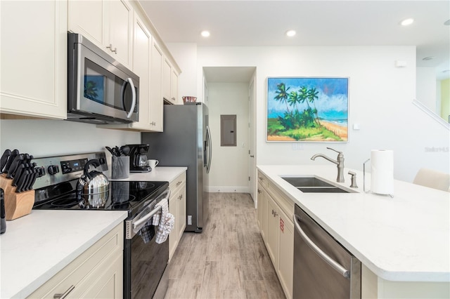 kitchen with sink, light hardwood / wood-style floors, white cabinets, and appliances with stainless steel finishes