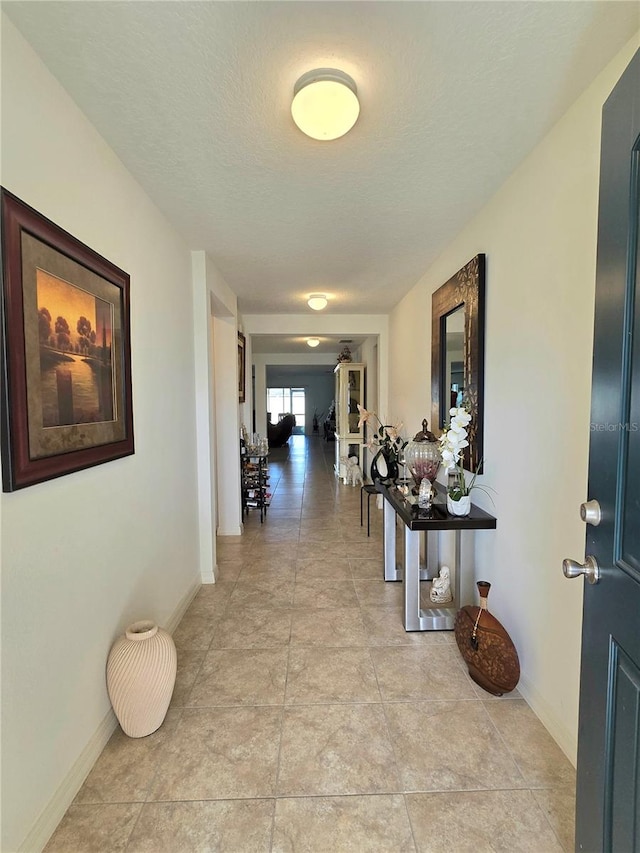 hallway featuring a textured ceiling and light tile floors