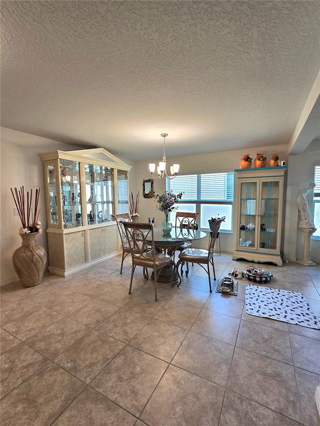 dining room featuring a healthy amount of sunlight, tile flooring, a textured ceiling, and an inviting chandelier