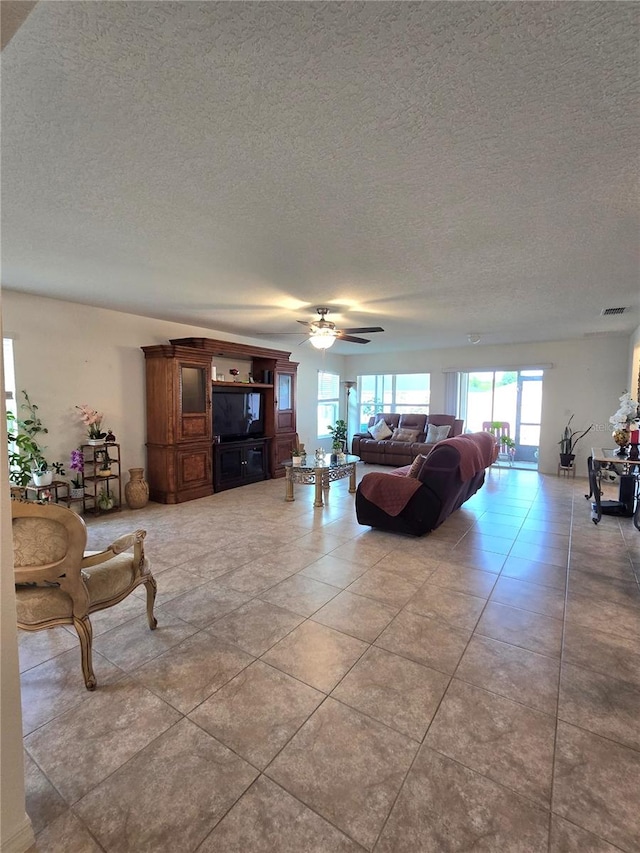 tiled living room with ceiling fan and a textured ceiling