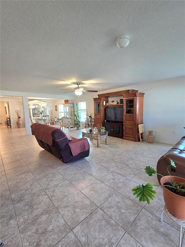 living room featuring a textured ceiling, ceiling fan, and light tile floors