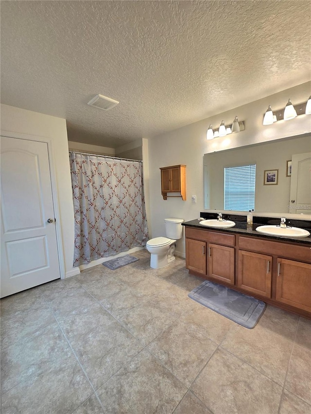 bathroom with tile floors, large vanity, double sink, and a textured ceiling