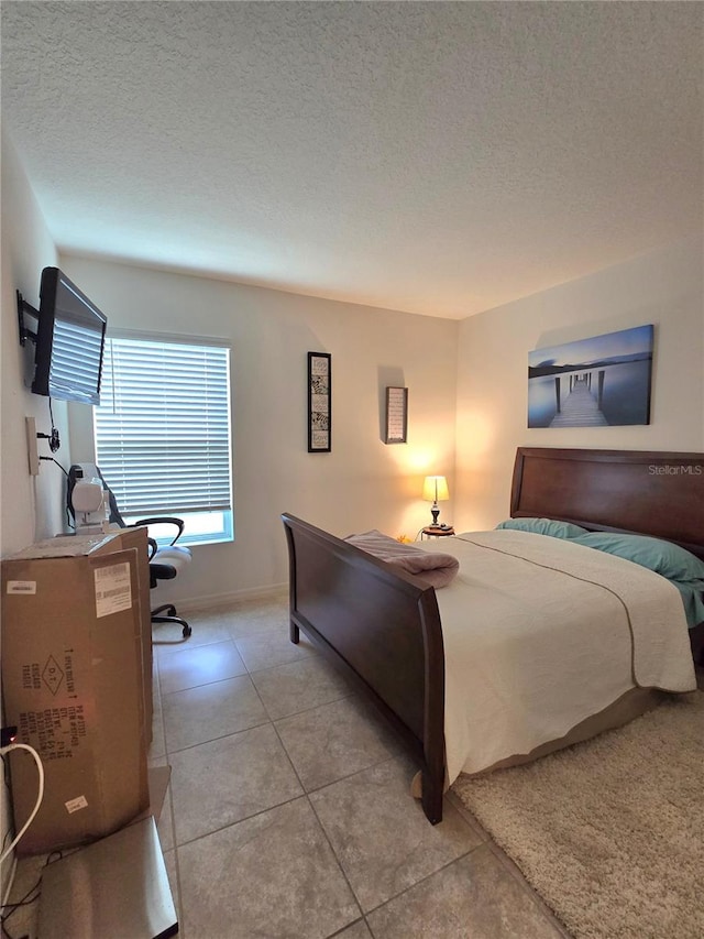 bedroom with a textured ceiling and tile floors