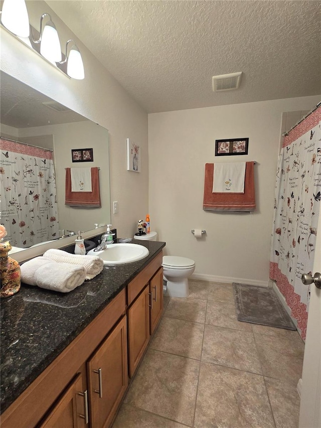 bathroom featuring tile flooring, vanity, toilet, and a textured ceiling