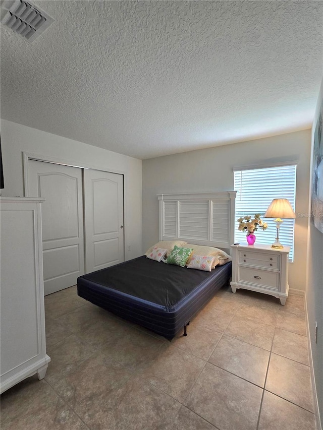 tiled bedroom with a closet and a textured ceiling