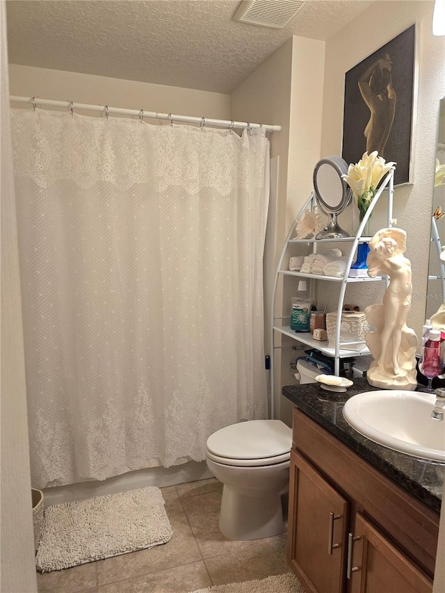 bathroom featuring a textured ceiling, vanity, toilet, and tile floors