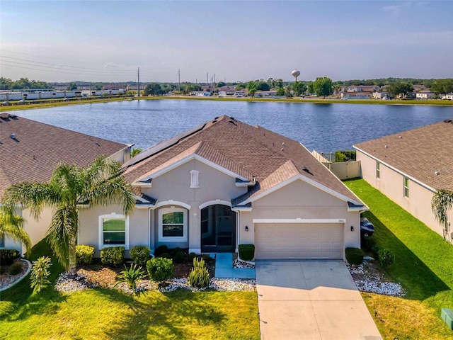 view of front of house featuring a garage, a front lawn, and a water view