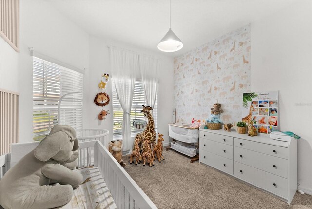 bedroom featuring light colored carpet and a nursery area