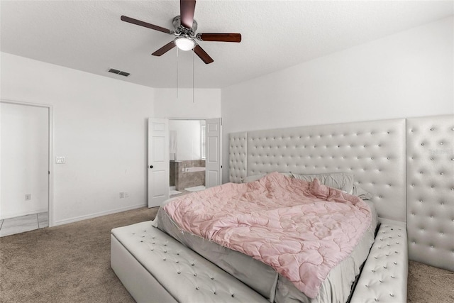 bedroom with carpet flooring, ensuite bath, ceiling fan, and a textured ceiling