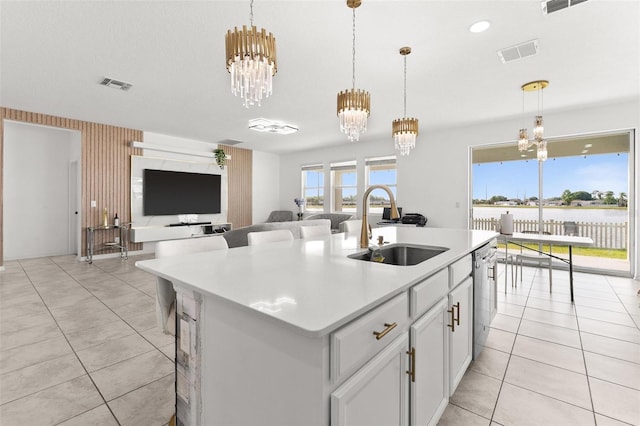 kitchen with sink, a kitchen island with sink, light tile floors, and hanging light fixtures