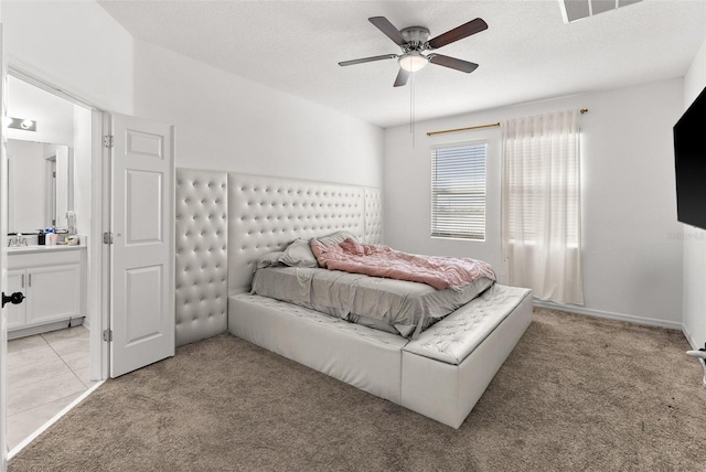 bedroom featuring light colored carpet, sink, ceiling fan, and a textured ceiling