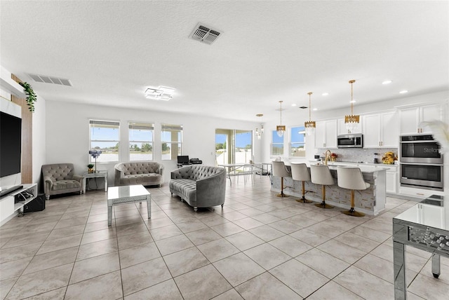 tiled living room featuring a chandelier, a textured ceiling, and sink