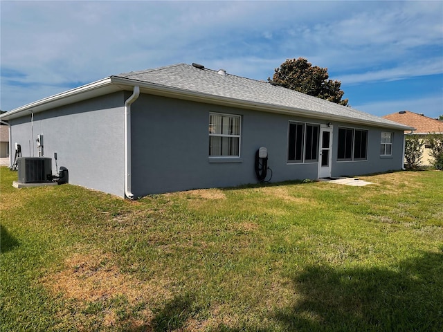 back of property with central AC unit and a lawn