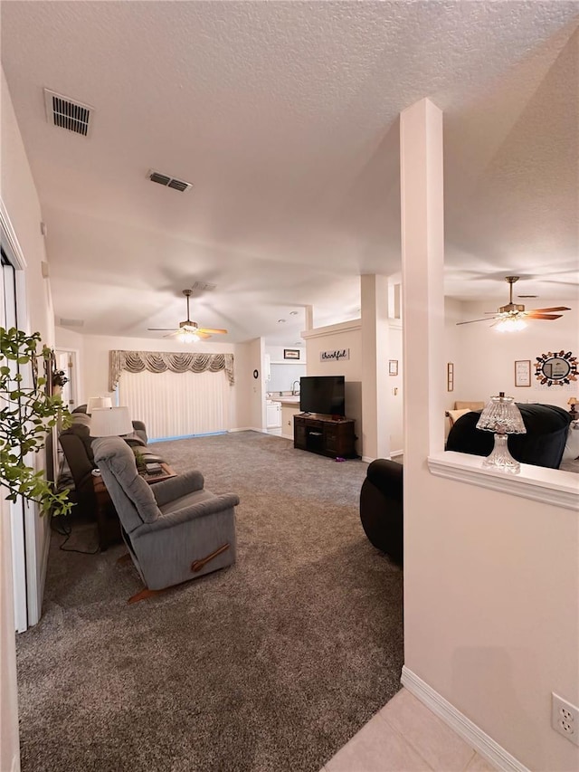 living room featuring carpet flooring, ceiling fan, and a textured ceiling