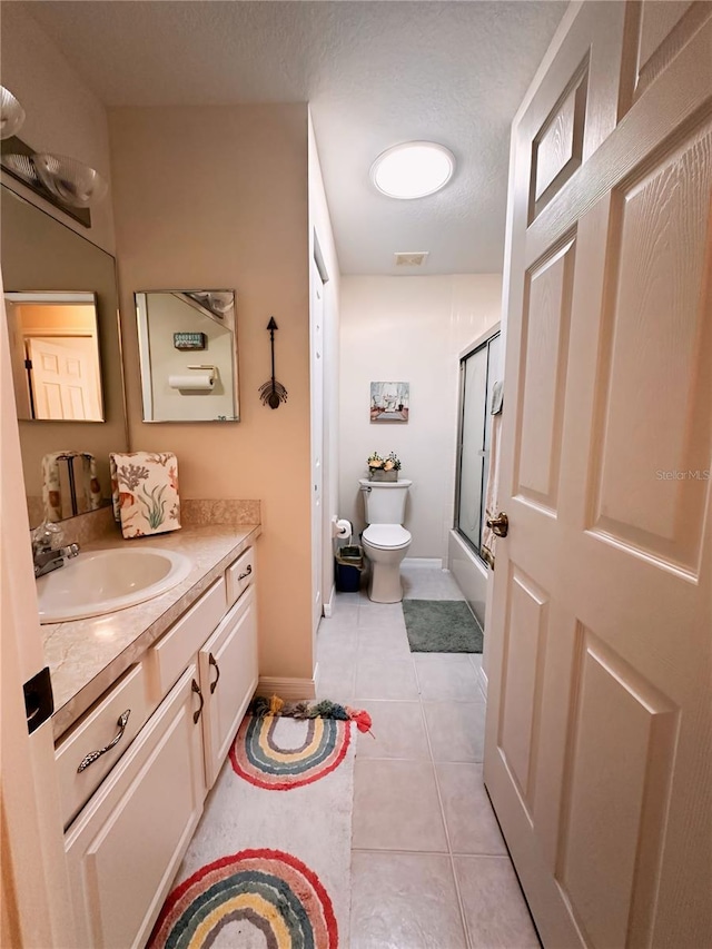 bathroom with tile flooring, vanity, toilet, and a textured ceiling