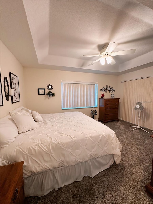 carpeted bedroom with ceiling fan and a raised ceiling