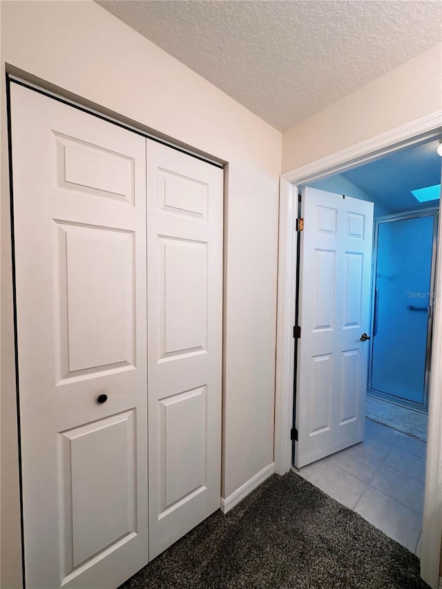 hall featuring a textured ceiling and tile flooring